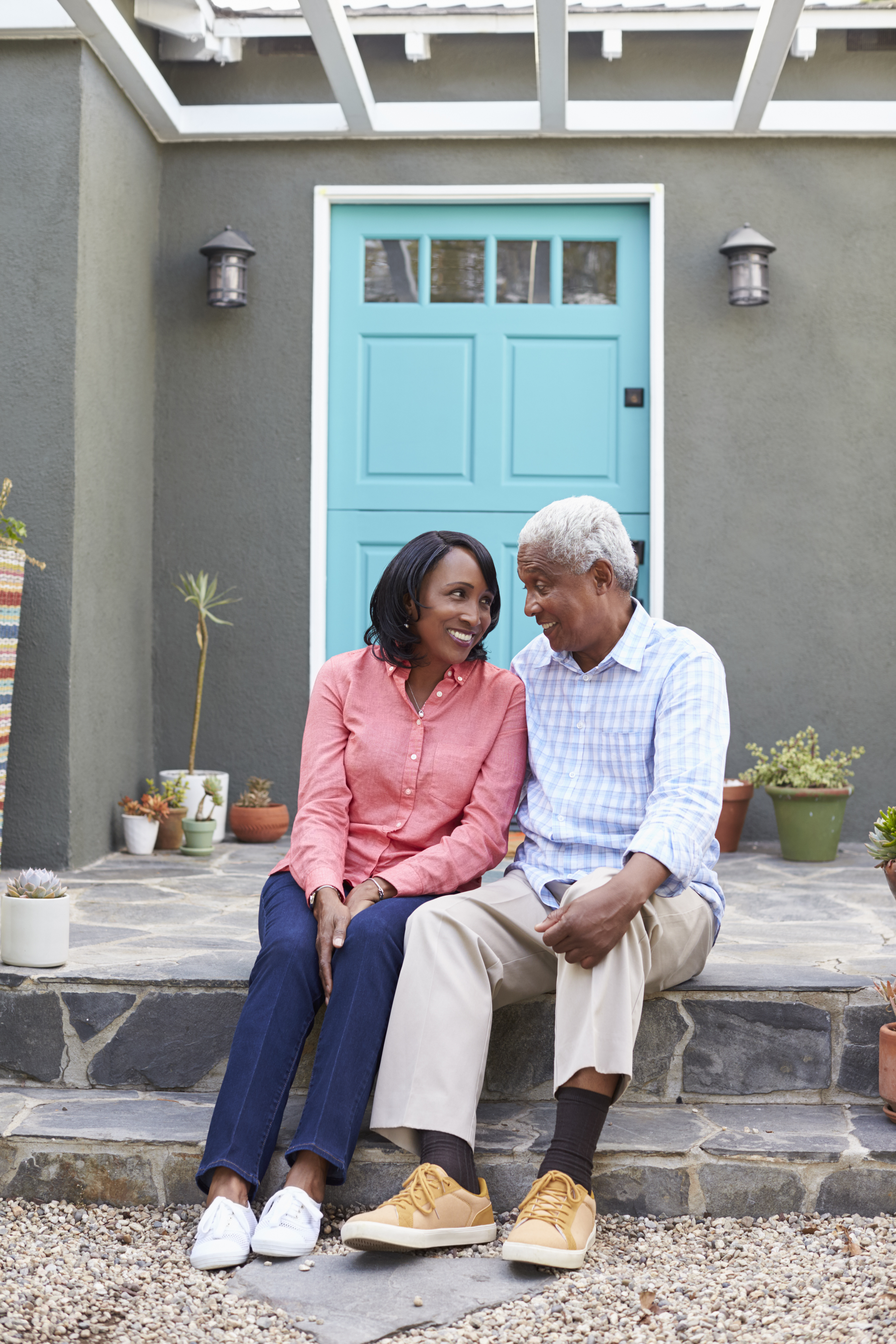 Senior couple sit on steps outside their house